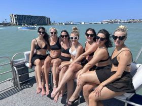 A fun group of friends enjoys a sunny day on the water, celebrating together on a boat — perfect for bachelorette parties or summer outings.