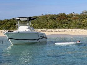 A person relaxes on a paddleboard near a boat in calm waters, showcasing a perfect beach day experience.
