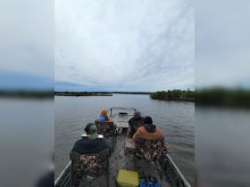 A group of friends relaxes on a boat, enjoying the serene waters and scenic views — perfect for a fishing trip or a day out in nature.