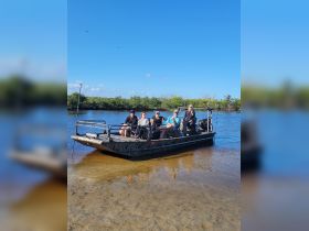 A lively group enjoys a day on the water aboard a flat-bottom boat, surrounded by lush mangroves — perfect for exploring nature and creating unforgettable memories.