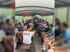 A lively group of travelers enjoys a boat tour, with a group leader engaging the audience — perfect for exploring scenic waterways and creating memorable experiences.