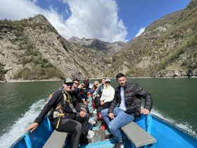 A lively group enjoys a boat ride through stunning mountainous scenery, capturing the essence of adventure on the water.
