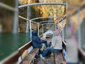A group of guests enjoys a scenic boat ride near a stunning waterfall, perfect for exploration and adventure on the water.