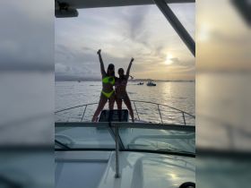 Two friends celebrate at sunset on a boat, capturing the joy of a perfect day on the water.