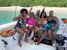 A joyful family enjoys their time on a boat, celebrating with a colorful spread of fruits and snacks — perfect for a fun day on the water.