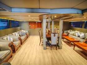 An elegant interior view of a boat's cabin featuring comfortable seating and a dining area, perfect for relaxing and enjoying meals while on the water.