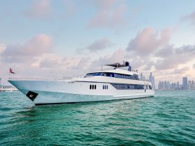 A stunning yacht cruising through clear waters, showcasing its sleek design against a backdrop of a vibrant skyline.