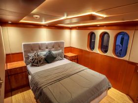 Cozy interior view of a boat cabin featuring a comfortable bed and stylish decor, perfect for relaxing during your maritime adventures.