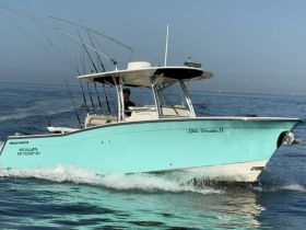 A sleek speedboat named 'Little Dreams II' glides through the water, showcasing its vibrant turquoise color and fishing gear, perfect for a day of adventure on the sea.