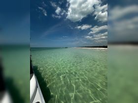 A serene view of clear turquoise waters with a boat in the distance, showcasing the beauty of a tranquil day on the water.