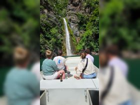 A group enjoys a scenic view of a stunning waterfall while relaxing on a boat, making for a perfect adventure on the water.