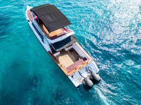 A stunning aerial view of a yacht cruising through crystal-clear waters, showcasing its elegant design and spacious deck — perfect for luxury outings.
