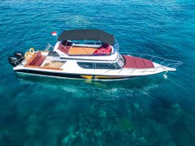A stunning aerial view of a sleek yacht cruising through crystal-clear waters, showcasing its elegant design and spacious deck — perfect for luxury charters.