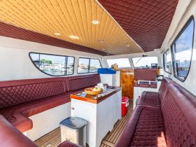 Interior view of a spacious boat cabin featuring comfortable seating and a well-equipped helm, perfect for relaxing during your maritime adventures.