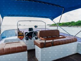 The interior of a boat featuring comfortable seating and a helm, perfect for navigating the waters in style and comfort.