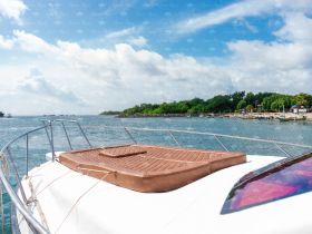 A serene view of a boat's deck featuring a comfortable sunbed, perfect for relaxing while enjoying the coastal scenery.