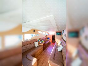 Interior view of a spacious boat cabin featuring comfortable seating and a cozy lounge area, perfect for relaxing during a day on the water.