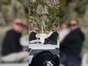 A cheerful group enjoys a scenic boat ride with a stunning waterfall in the background, perfect for nature lovers and adventure seekers.