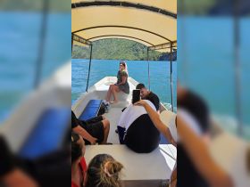 A lively group enjoys a boat ride, capturing moments and smiles against a stunning backdrop of water and greenery.