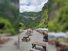 A scenic view of a beach area surrounded by lush mountains, with guests enjoying the space — perfect for relaxation and outdoor activities.