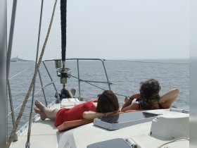 Two friends relax on the deck of a yacht, enjoying the sun and sea views — a perfect moment for unwinding on the water.