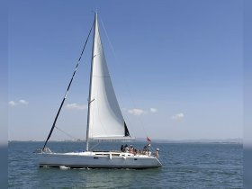 A lively group enjoys a sailing adventure on a yacht, showcasing the joy of on-water activities under a clear blue sky.