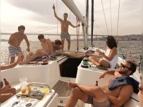 A lively group enjoys a fun day sailing, celebrating with drinks and laughter on the deck of a yacht, creating unforgettable memories on the water.