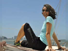 A woman enjoys a sunny day on a sailboat, capturing the essence of relaxation and adventure on the water.