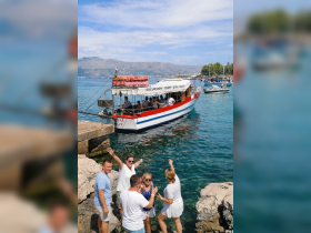 A lively group enjoys their excursion by the water, waving at the camera as their boat approaches the dock — a perfect moment of fun and adventure.