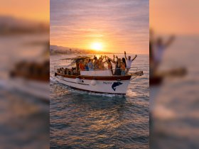 A lively group celebrates aboard the boat 'Nera' at sunset, raising their drinks in a joyful toast — a perfect moment for unforgettable gatherings on the water.