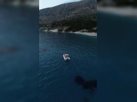 A scenic view of a boat with guests enjoying the water, set against a beautiful coastline — perfect for exploring hidden beaches and enjoying the outdoors.