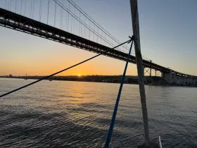 A stunning sunset view from a boat, featuring a bridge silhouetted against the colorful sky — perfect for capturing the beauty of evening cruises.