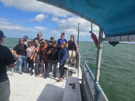 A lively group poses for a photo on a boat, capturing a moment of fun and celebration on the water.