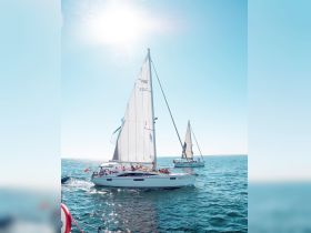 A lively sailing experience with a group enjoying the sun aboard a yacht, navigating through sparkling ocean waters.