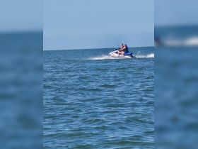 A couple enjoys an exhilarating ride on a jet ski, creating waves in the open water — a perfect snapshot of adventure on the sea.