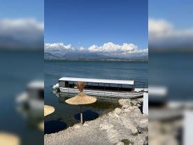 A scenic view of a boat docked by the shore, surrounded by tranquil waters and mountains in the background, perfect for exploring the area's natural beauty.