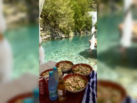 A beautifully arranged spread of fresh salads and drinks set against a stunning turquoise backdrop, perfect for a relaxing day on the water.