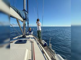 A couple enjoys a serene sailing experience on the open ocean, capturing the essence of adventure and tranquility at sea.