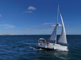 A lively group enjoys a sailing adventure on a beautiful day, with the boat gliding through the sparkling ocean waters.