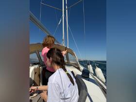 Two guests enjoy a sunny day sailing on a yacht, capturing the moment with their phones — a perfect blend of relaxation and adventure on the water.