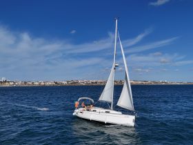 A group of friends enjoys a sailing adventure on a beautiful day, with the coastline in the background — perfect for memorable outings on the water.