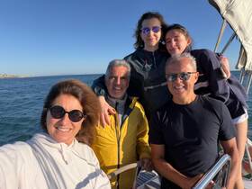 A joyful family poses for a selfie on a boat, capturing a memorable moment on the water with smiles all around.