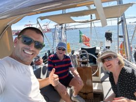 A cheerful group enjoys a sunny day on a sailboat, capturing a fun selfie while celebrating their time on the water.