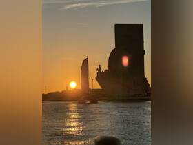 A stunning sunset view featuring a sailboat and a landmark silhouette, capturing the essence of a perfect evening on the water.