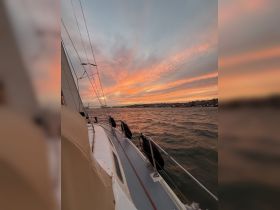 A stunning sunset view from the deck of a yacht, showcasing the tranquil waters and distant city lights — perfect for evening cruises.