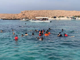 A vibrant group of snorkelers explores the clear waters, enjoying a day of swimming and adventure at a beautiful beach destination.