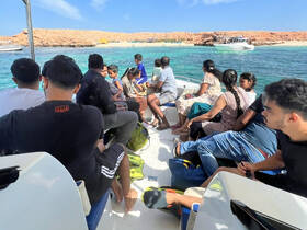 A lively group of families enjoys a boat ride, surrounded by stunning turquoise waters and scenic views — perfect for a day of adventure on the water.