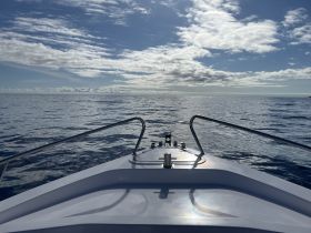 A serene view from the front of a boat cruising on calm waters, showcasing a beautiful sky and tranquil sea — perfect for a peaceful day on the water.