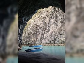 A serene view of a boat anchored in a tranquil cove, surrounded by stunning rock formations — perfect for exploring hidden gems in nature.
