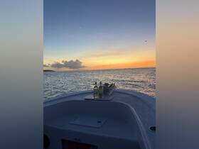 A serene sunset view from the bow of a boat, featuring two bottles of wine, perfect for a relaxing evening on the water.